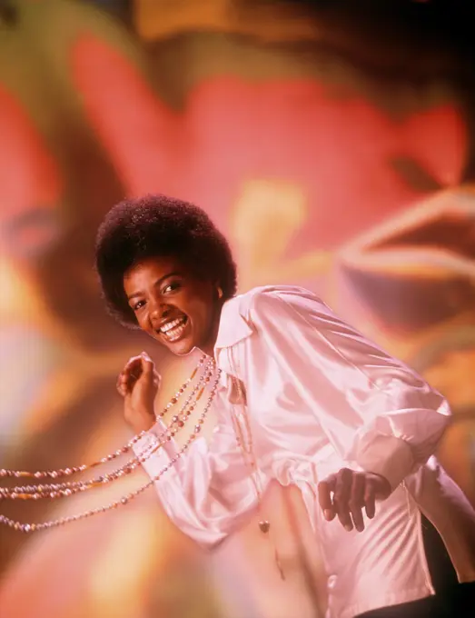 1970s LAUGHING YOUNG AFRICAN AMERICAN WOMAN AFRO HAIR STYLE WHITE SILK SHIRT SINGING DANCING BEADS SWINGING LOOKING AT CAMERA