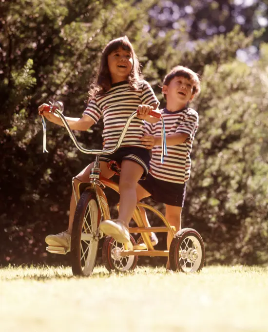 1970s 2 KIDS STRIPED TEE SHIRTS SHORTS RIDING YELLOW TRICYCLE BIKE GIRL STEERING BOY STANDING BACK BIKE