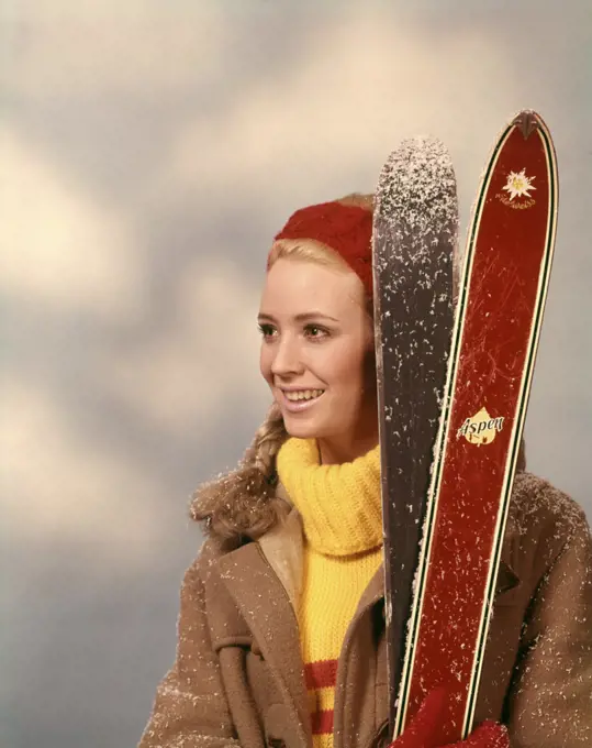 1960s 1970s PORTRAIT WOMAN RED HEADBAND YELLOW TURTLENECK SWEATER HOLDING PAIR OF SKIS SKIER