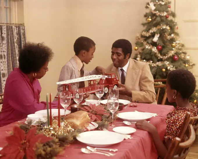 1970s AFRICAN AMERICAN FAMILY AT CHRISTMAS HOLIDAY DINNER TABLE FATHER MOTHER SON AND DAUGHTER