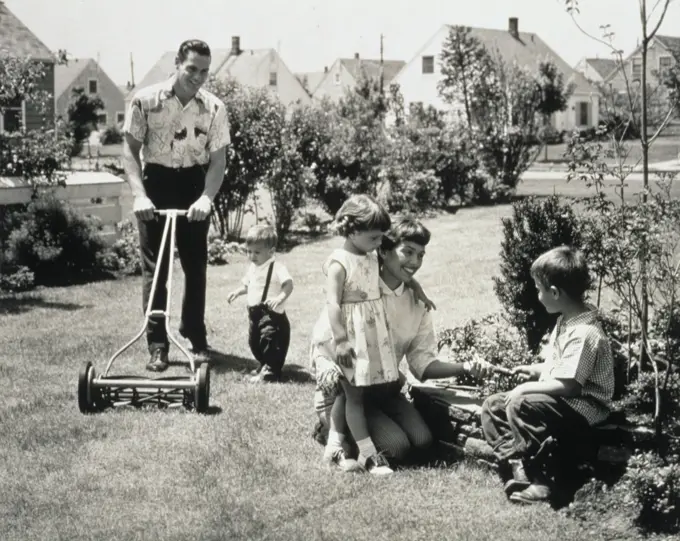 1950S Family In Backyard Dad And Toddler Cutting Grass Mom And Kids Gardening