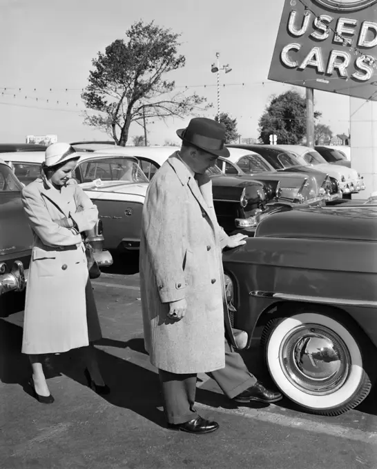 1950S Couple In Used Car Lot Man Kicking Tire