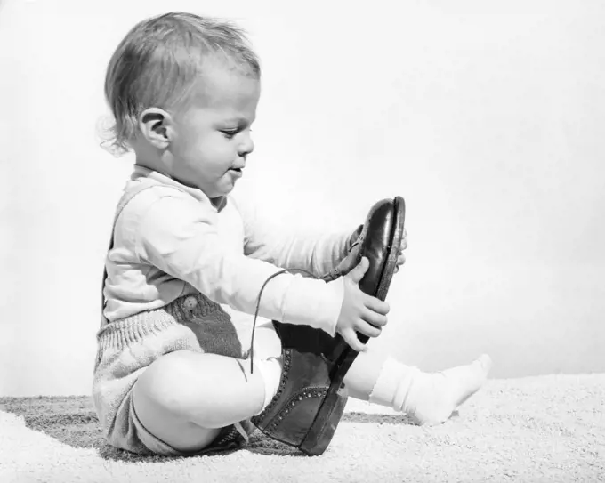 1960s BABY BOY TRYING TO PUT ON ADULT MAN'S SHOE