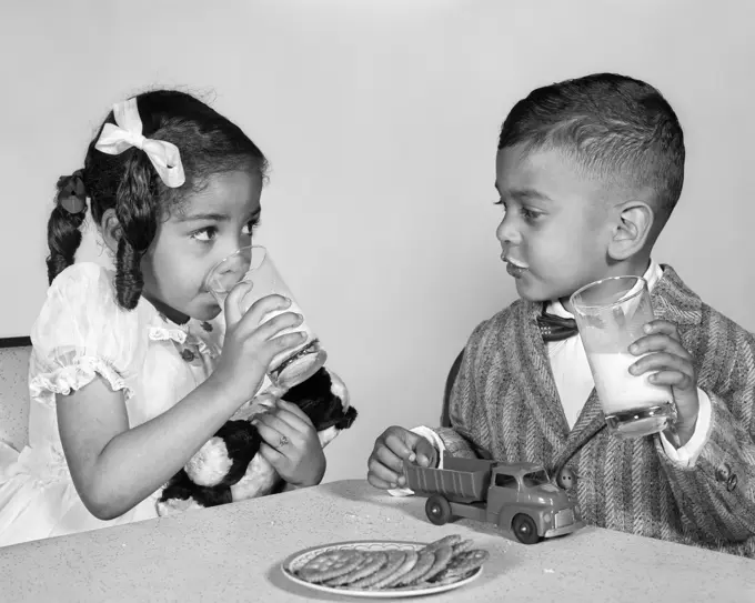 1960s AFRICAN AMERICAN GIRL BOY DRINKING MILK EATING COOKIES