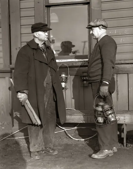 1920s 1930s TWO RAILROAD WORKERS HOLDING LANTERNS & FLAGS A FLAGMAN CONDUCTOR AND A BRAKEMAN MEETING AND TALKING