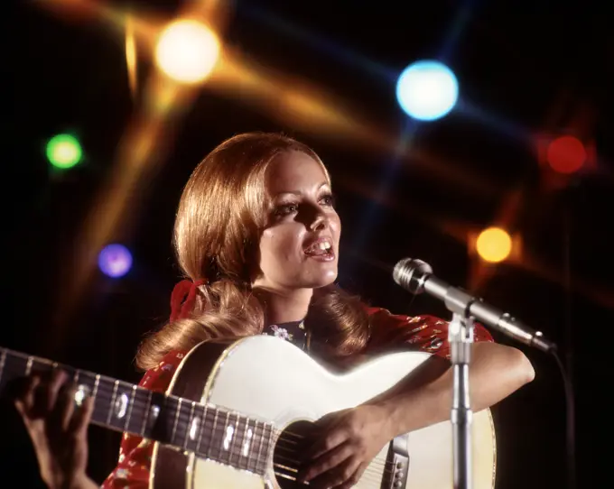 1970s WOMAN PLAYING GUITAR SINGING INTO MICROPHONE COLORED SPOTLIGHTS