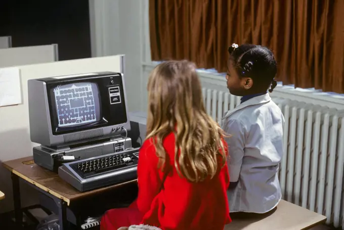 1980s TWO GIRLS LEARNING ABOUT COMPUTERS BY PLAYING ON SCREEN GAME