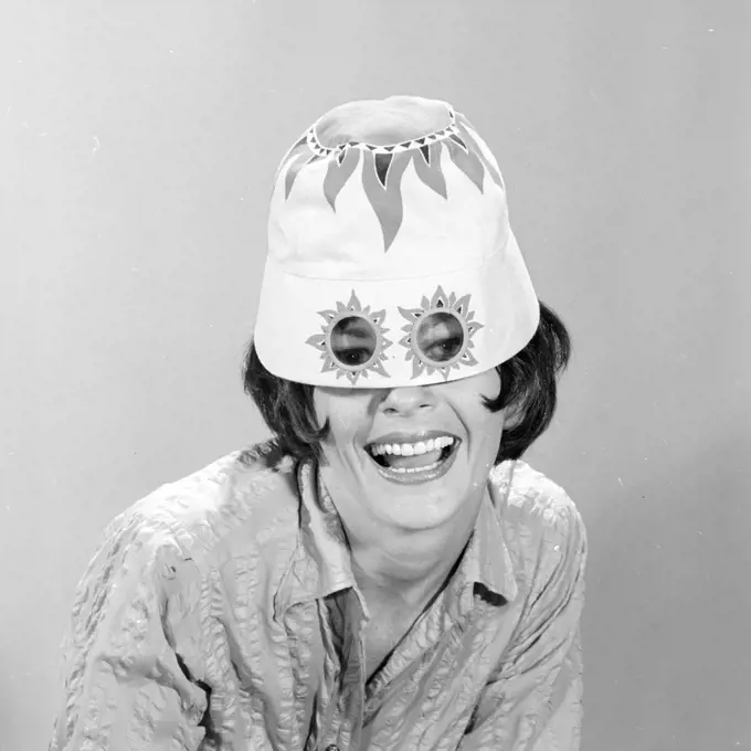 1960s SMILING WOMAN WEARING FUNNY WACKY SUN HAT WITH SUNSPOTS FOR EYEGLASSES LOOKING AT CAMERA