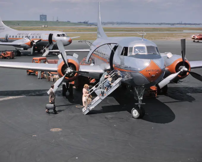 1950s TWO AMERICAN AIRLINE PROPELLER AIRPLANES ON TARMAC WITH PASSENGERS CLIMBING ABOARD LAGUARDIA AIRPORT NEW YORK USA