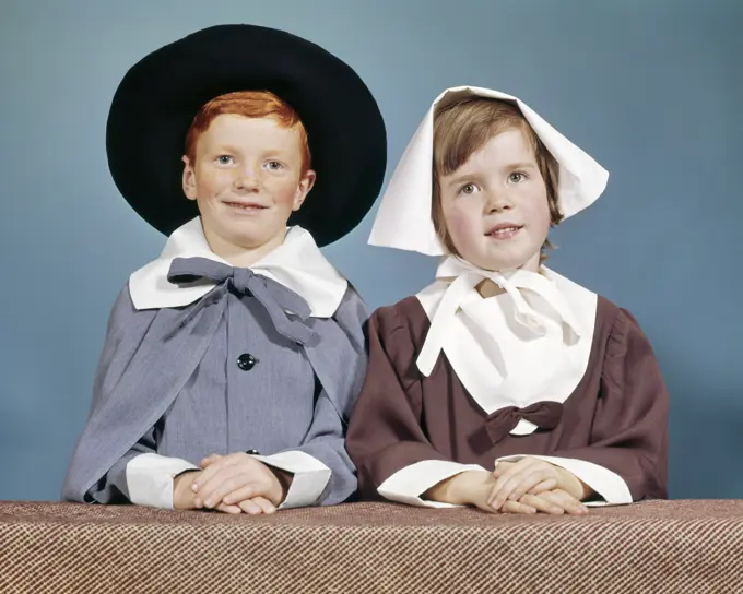 1950s 1960s BOY GIRL IN PILGRIM COSTUMES FOR ELEMENTARY SCHOOL THANKSGIVING PLAY LOOKING AT CAMERA