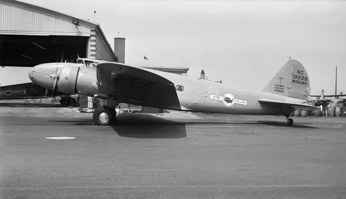 1930s UNITED AIRCRAFT CORPORATION BOEING 247 AIRPLANE ON TARMAC IN FRONT OF HANGAR