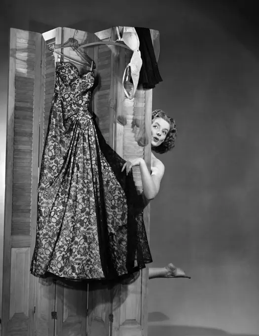 1950S Woman Peeking From Behind Screen At Evening Gown Getting Dressed