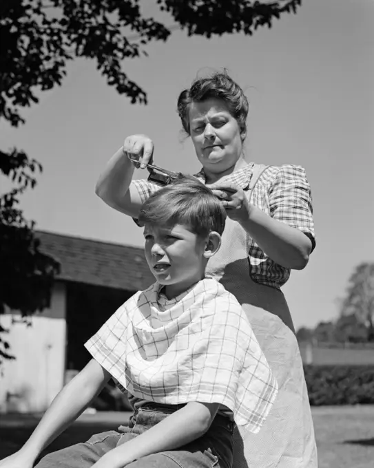 1940S Mother Cutting Son'S Hair Outdoors