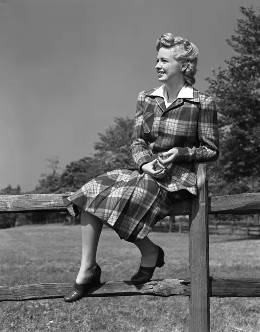 1940S Full Length Portrait Of Blond Woman Sitting On A Wooden Fence Wearing Plaid Tartan Suit