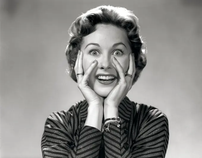 1950S 1960S Portrait Of Wacky Woman Hands On Face With Smiling Excited Happy Funny Face Surprised Expression Looking At Camera