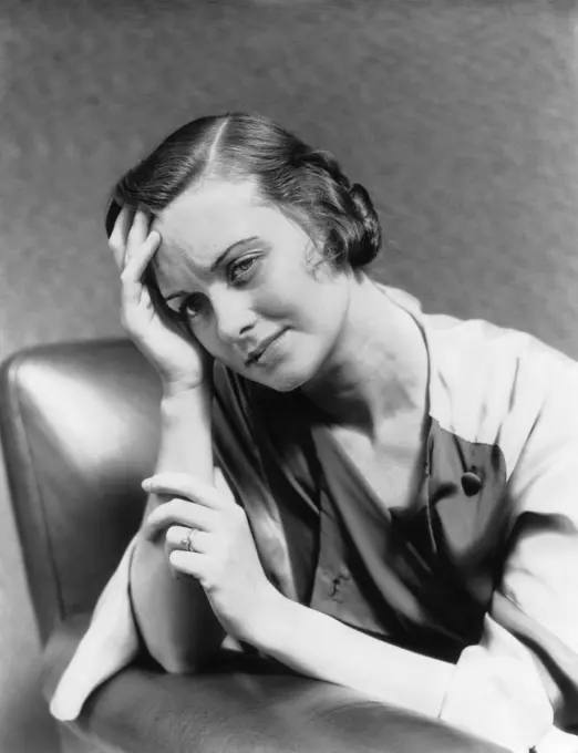 1930S 1940S Woman Sitting In Chair Worried Sad Expression One Hand Up To Her Forehead  