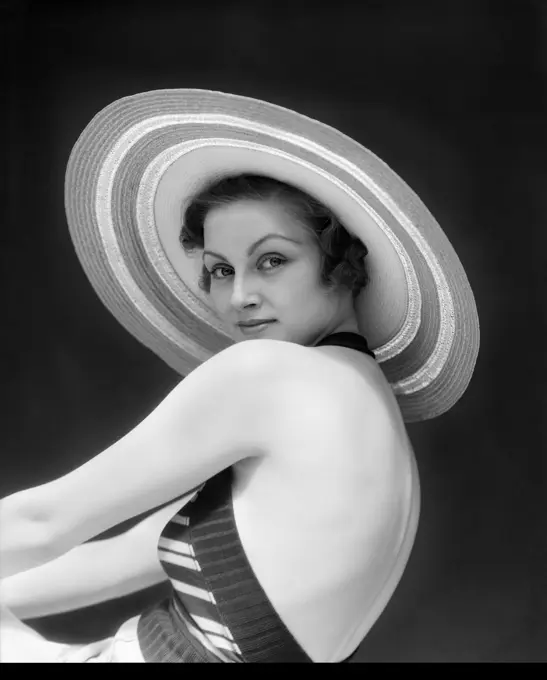 1930S Woman Wearing A Striped Halter Top & Wide Brim Striped Straw Hat Looking Over Shoulder