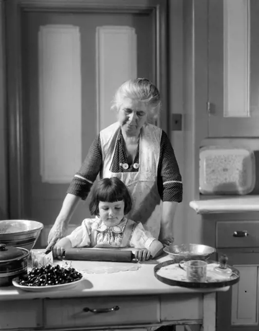 1920S 1930S Grandmother Baking Cherry Pie Teaching Granddaughter To Use Rolling Pin