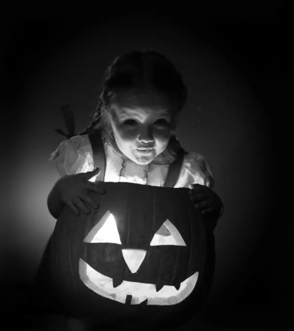 1950S Little Girl Standing Over Carved Pumpkin Face Lit By Candle