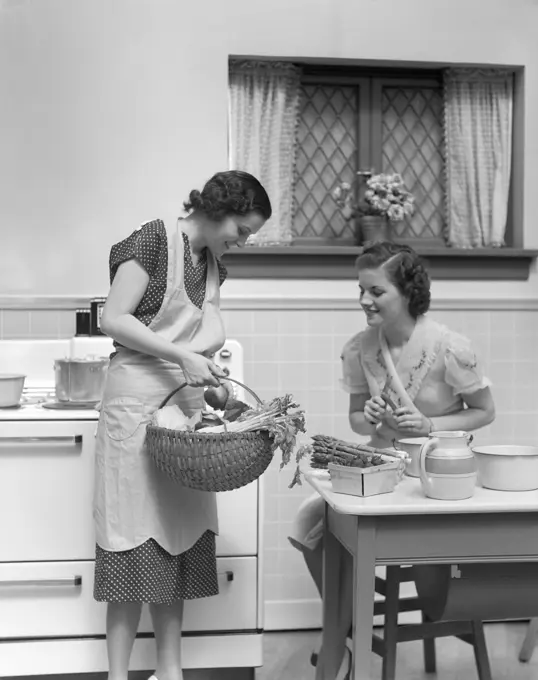 1930S 1940S Two Women At Kitchen Table With A Basket Of Vegetables Asparagus Stove