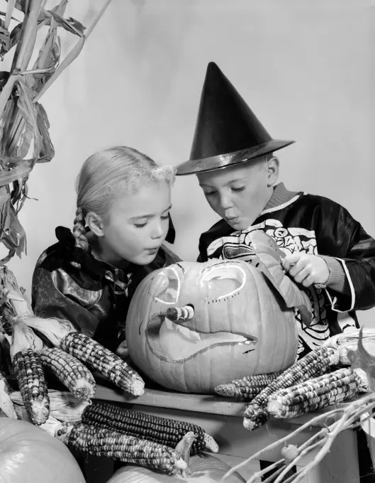 1960S Boy And Girl In Halloween Costumes Looking Into Pumpkin Indoor