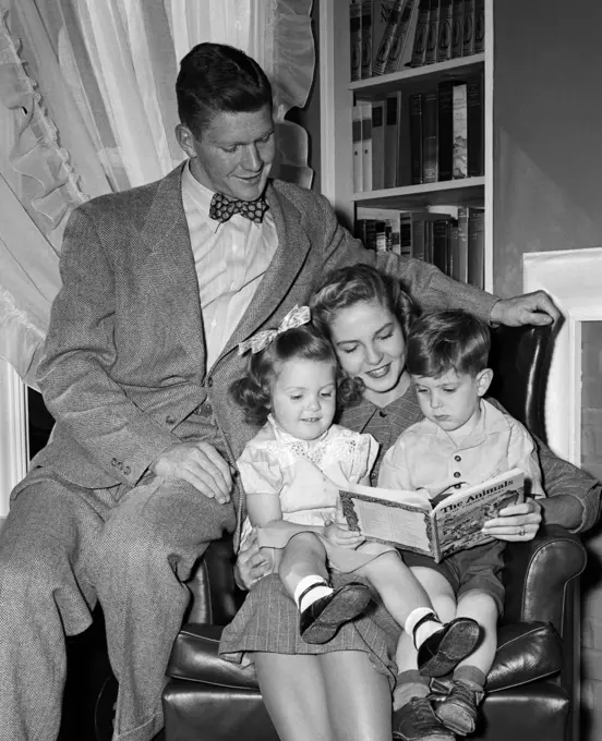 1940S Woman Mother In Armchair Reading To Boy Son Girl Daughter With Proud Man Father Watching