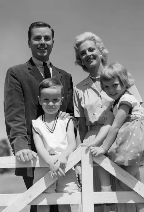 1950S 1960S Portrait Smiling Family Father Mother Son Daughter Behind White Fence Outdoor