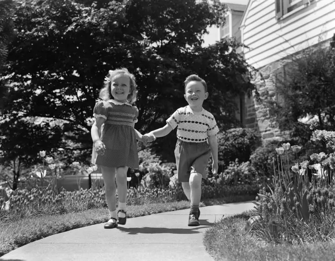 1950S Two Children Holding Hands Smiling Walking Along Sidewalk