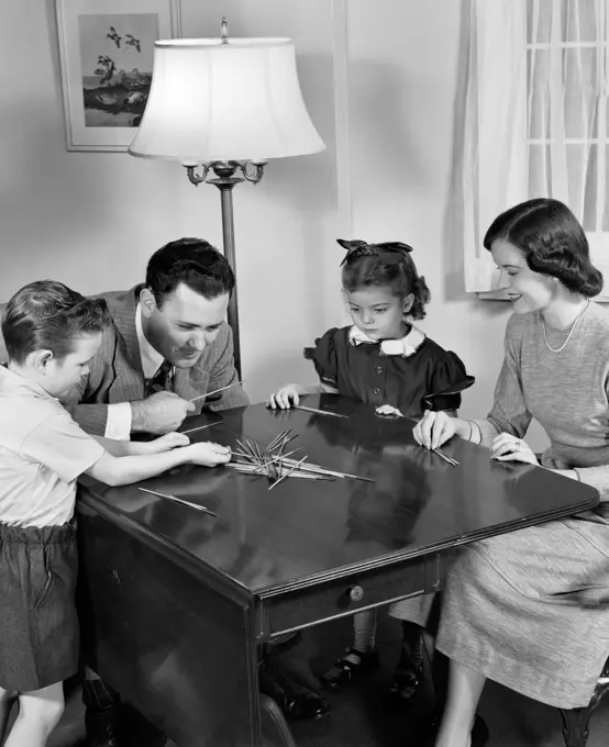 1940S Parents Playing Pick Up Sticks Game With Young Son And Daughter Indoor