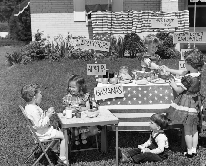 1950S Kids In Backyard Playing Store With Signs Selling Apples Bananas Sandwiches Lollypops