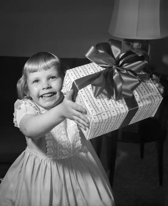 1950S Smiling Girl Holding Up Gift Wrapped Present