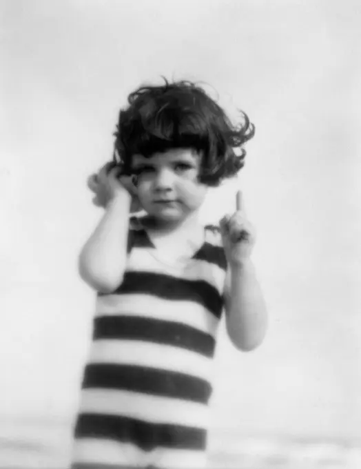 1920S Girl In Striped Bathing Suit Holding Seashell Up To Ear