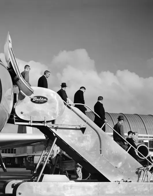 1960S Line Of Businessmen Walking Down Stairway Off Jet Airplane