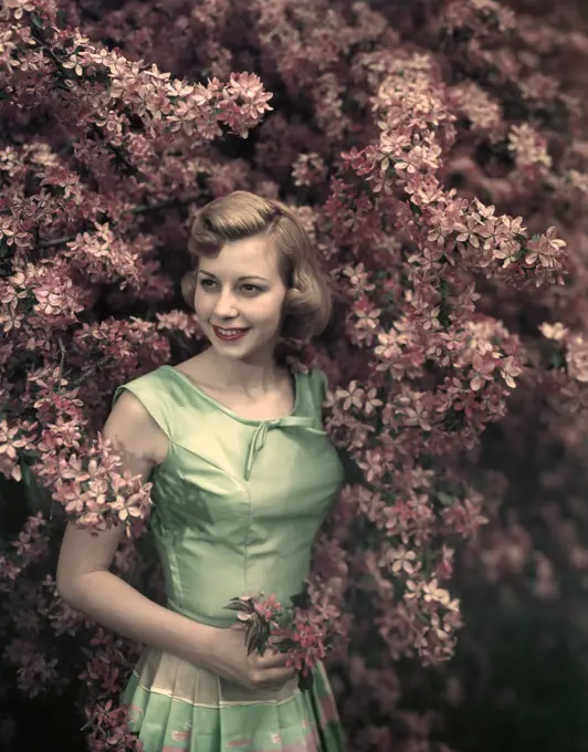 1950S Portrait Smiling Woman Standing Next To Flowering Tree