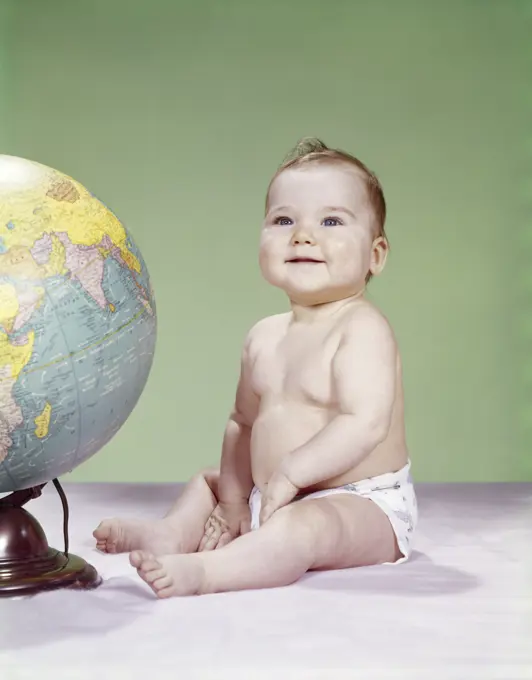 1960S Smiling Baby Wearing Diaper Sitting Beside Earth Globe