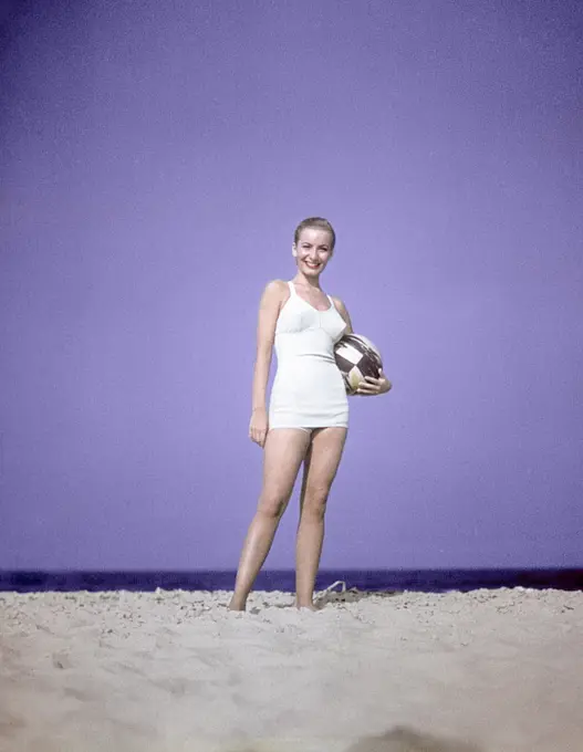 1950S Full Length Portrait Woman Light Blue One Piece Bathing Suit Swim Wear Standing On Sand Holding Beach Ball Fashion