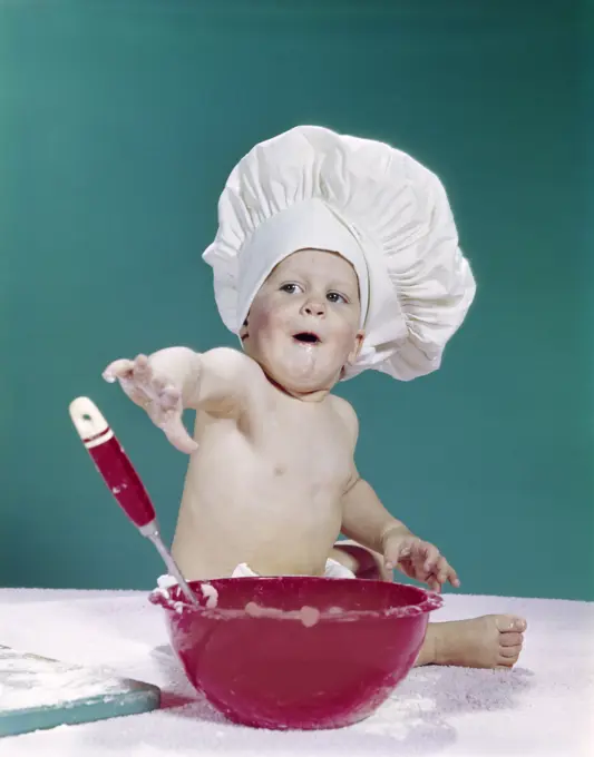 1960S Baby Wearing Chef Hat With Red Mixing Bowl And Spoon Funny Facial Expression