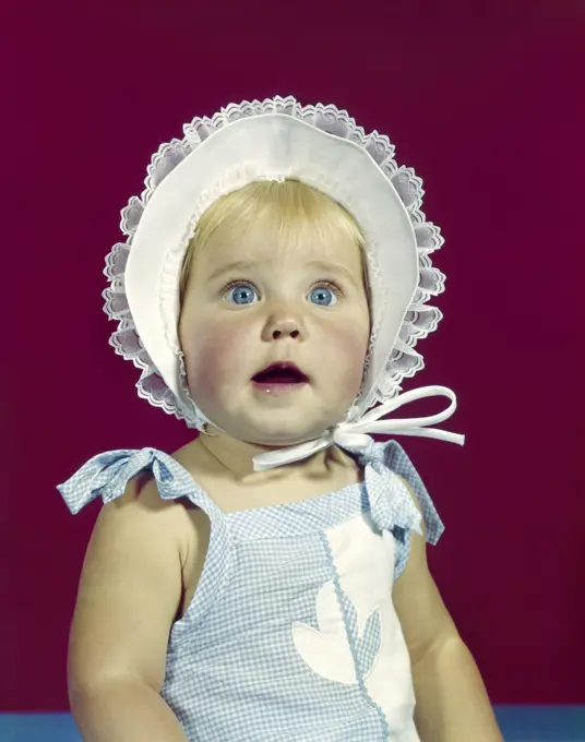 1960S Blonde Baby Blue Eyes Wearing Ruffled Bonnet Facial Expression Of Wonder  