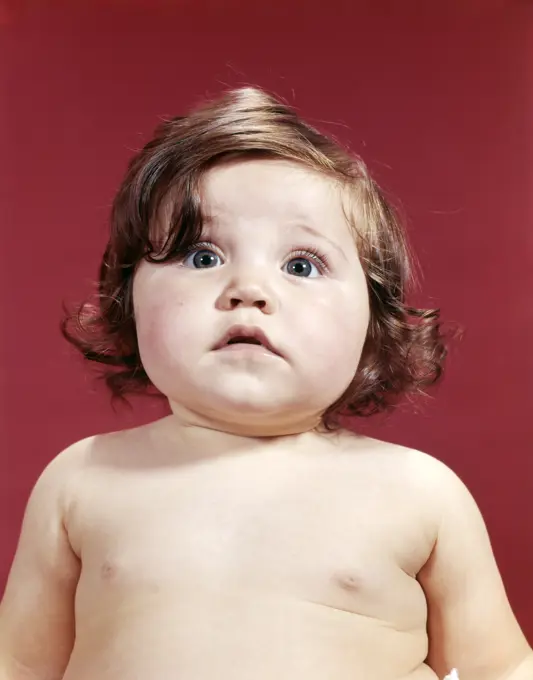 1960S Portrait Brunette Baby Girl With Chubby Round Face Uncertain Facial Expression