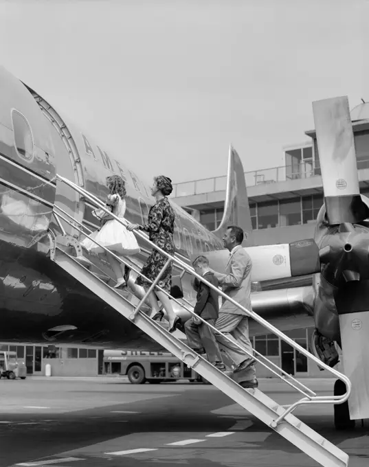 1950S Family Father Mother Daughter Son Boarding Propeller Airliner By Climbing Gangway Stairs At Airport