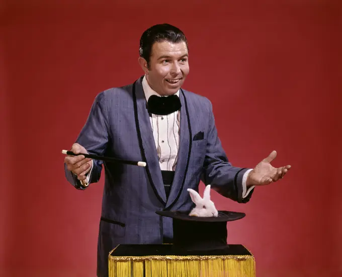 1970S Man Magician Waving Wand Over Top Hat Inverted On Table Flowers Appear Magic