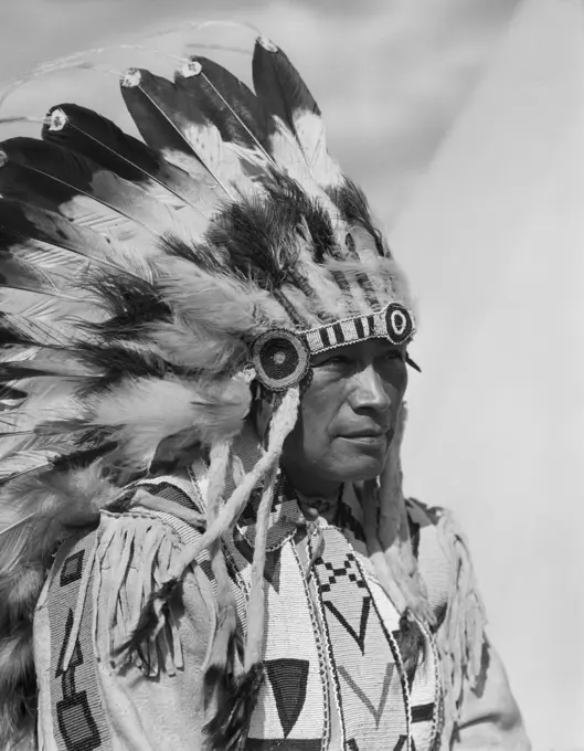 1920s PORTRAIT NATIVE AMERICAN MAN WEARING FULL FEATHER HEADDRESS STONEY SIOUX ALBERTA CANADA