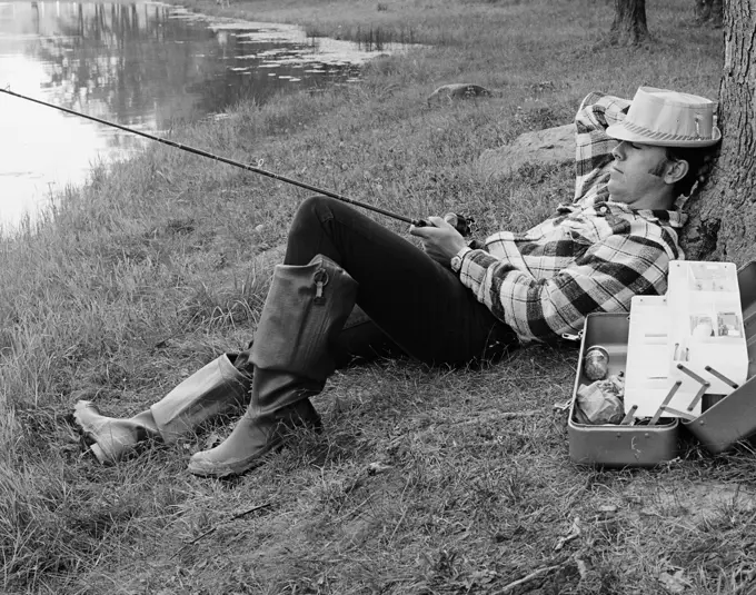 1970S Man Sleeping Against A Tree Trunk While Fishing In A Lake