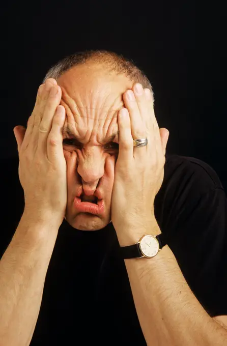 PORTRAIT OF STRESSED MAN SCRUNCHING UP FACE WITH HANDS