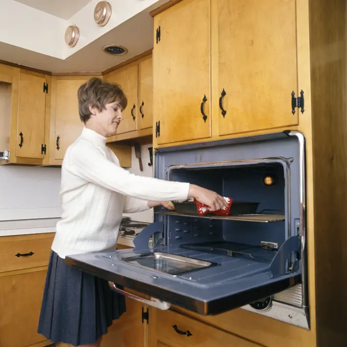 1970S Smiling Housewife In Kitchen Taking Baking Dish Out Of Wall Mounted Oven