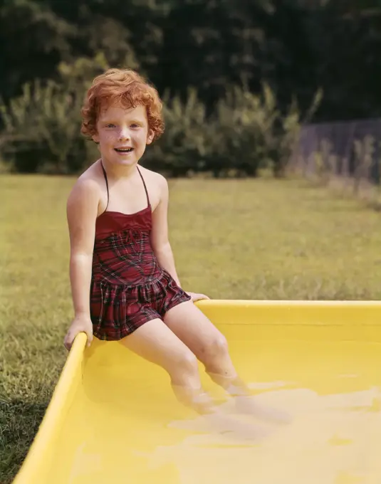 1960S Smiling Red Haired Little Girl In Plaid Bathing Suit Sitting On Yellow Plastic Backyard Swimming Pool