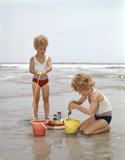 Two Girls Playing In Sand At Beach