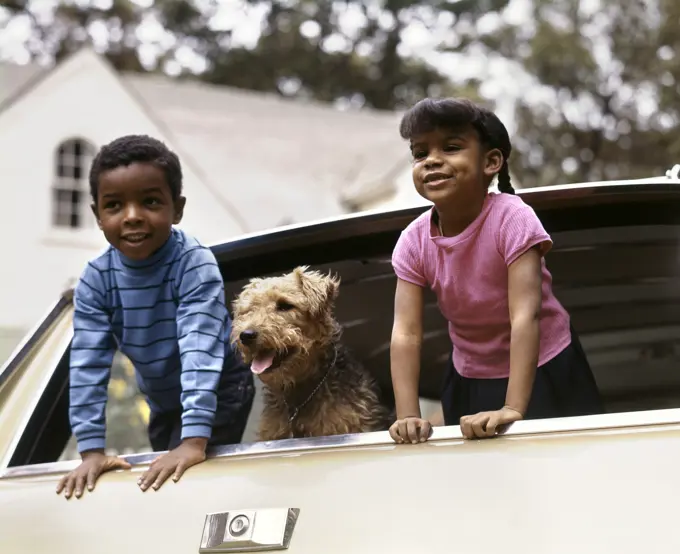 1970S Smiling African American Boy And Girl And Airedale Dog Leaning Out Of Station Wagon Rear Window