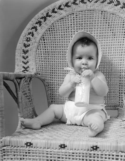 1940S Baby Sitting In Wicker Chair Sucking Milk Bottle