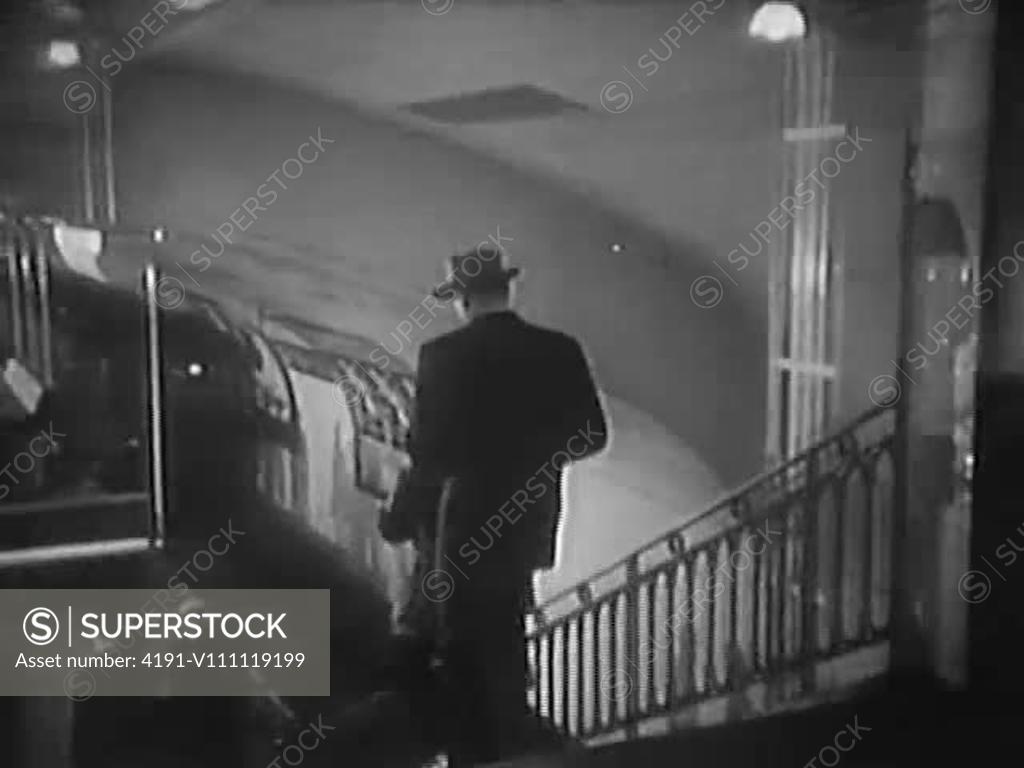 Panning shot of men running down steps towards railway platform ...